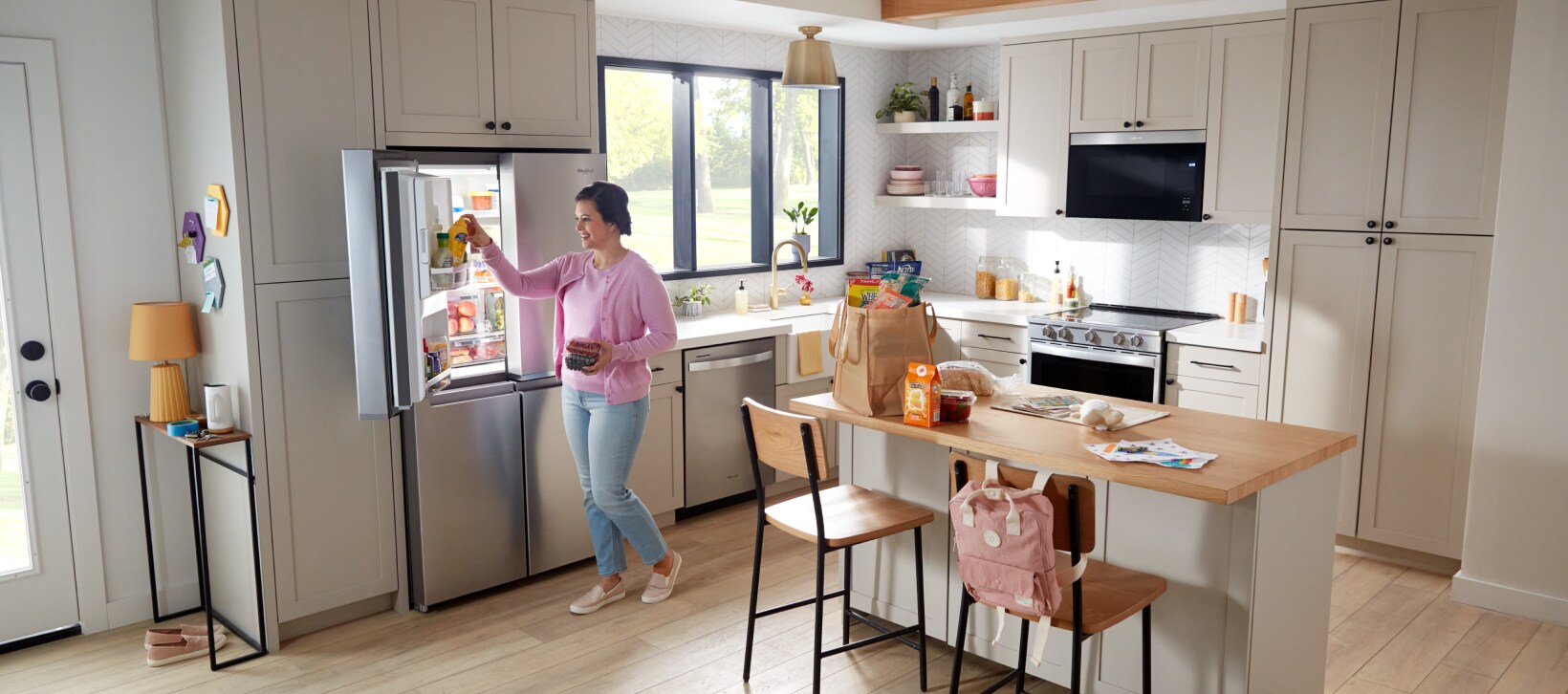 A person unloading groceries in a kitchen with Whirlpool® appliances