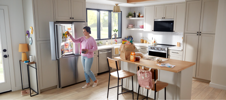 A person unloading groceries in a kitchen with Whirlpool® appliances
