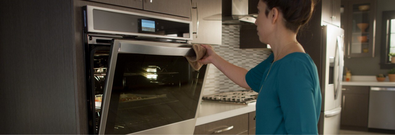 A woman opens a Whirlpool® wall oven. A woman opens a Whirlpool® wall oven.