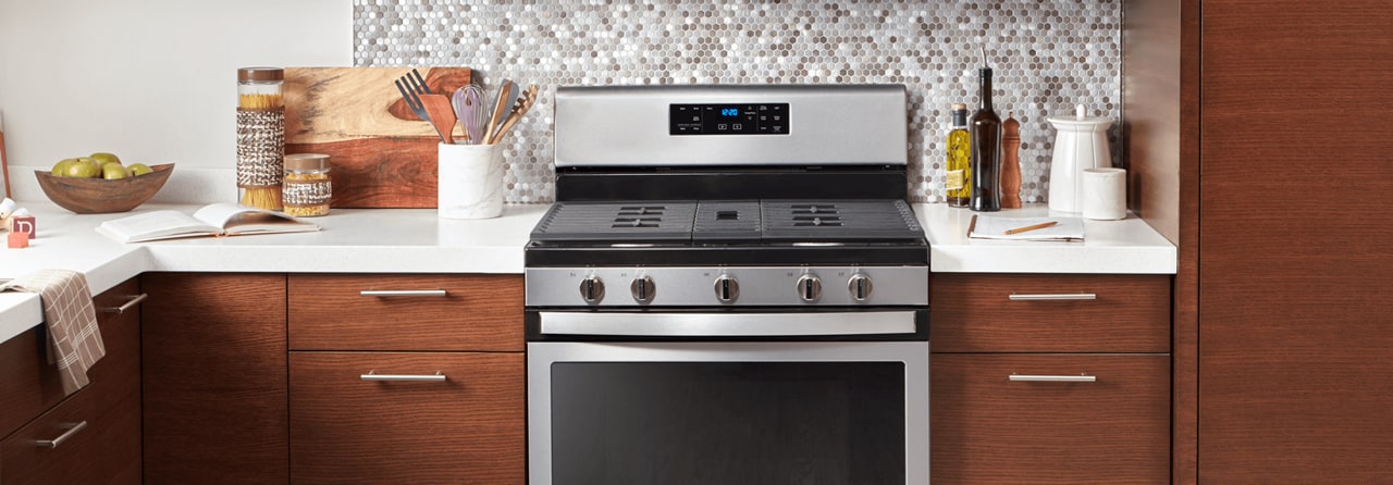 A five burner range with a stainless steel finish between two cabinets. A five burner range with a stainless steel finish between two cabinets.