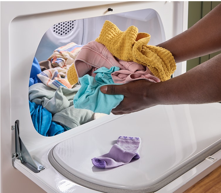 A person taking clothes out of a Whirlpool® Dryer
