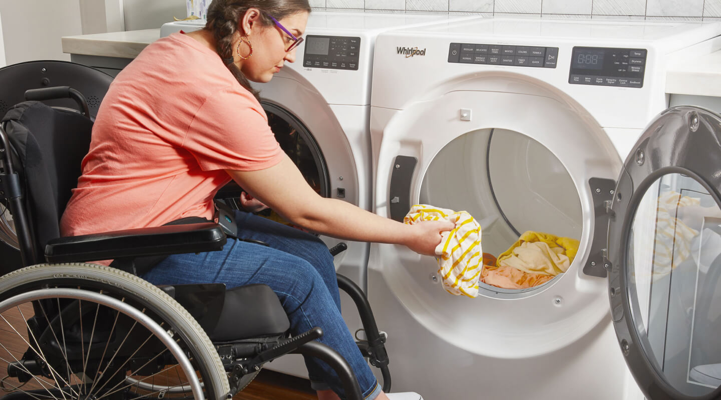 Person in a wheelchair loading a dryer Person in a wheelchair loading a dryer