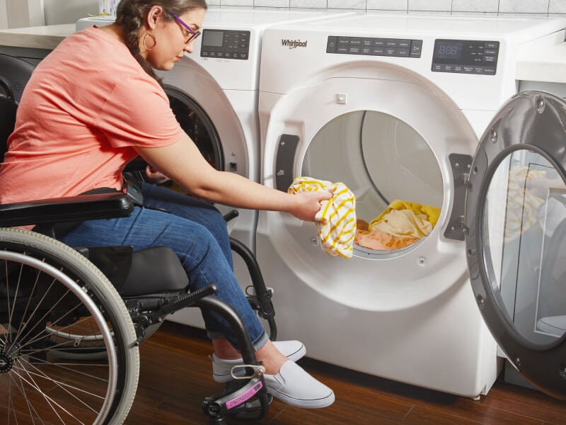 Person in a wheelchair loading a dryer Person in a wheelchair loading a dryer