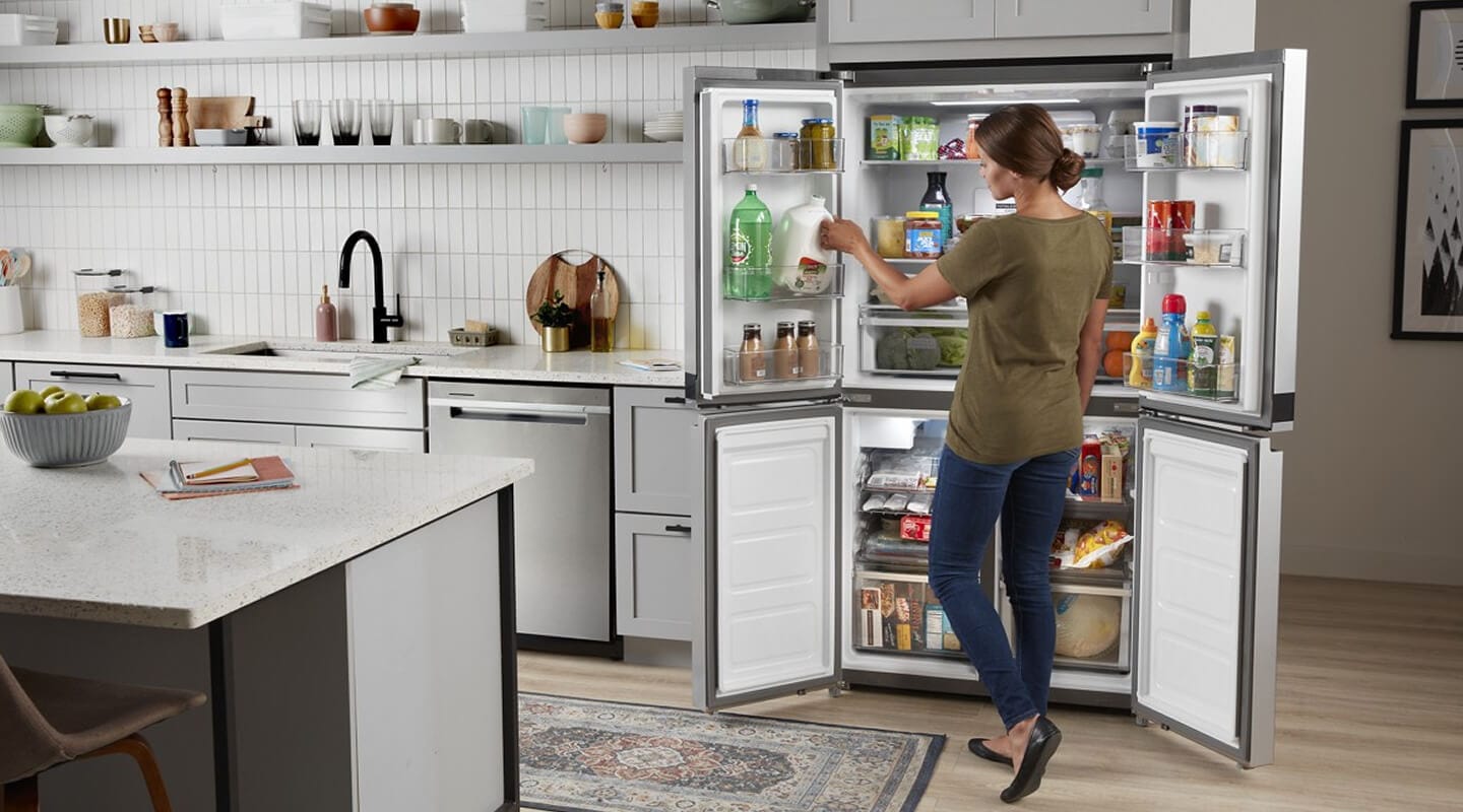Person stocking the in-door shelving of an open Whirlpool® 4-Door Refrigerator Person stocking the in-door shelving of an open Whirlpool® 4-Door Refrigerator