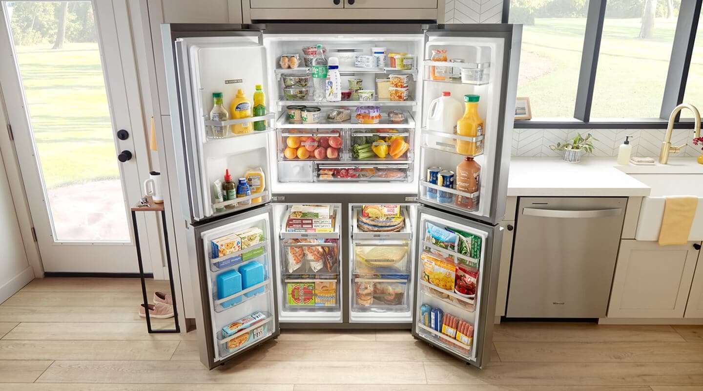 Fully stocked, open 4-door refrigerator built into tan cabinetry Fully stocked, open 4-door refrigerator built into tan cabinetry