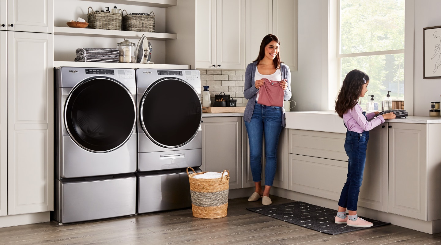 Child and adult doing laundry in a laundry room Child and adult doing laundry in a laundry room