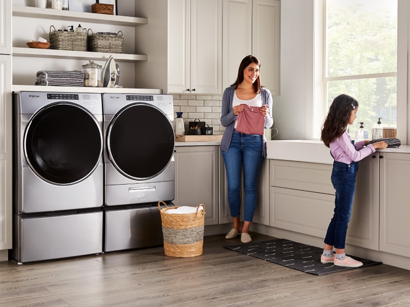 Child and adult doing laundry in a laundry room Child and adult doing laundry in a laundry room