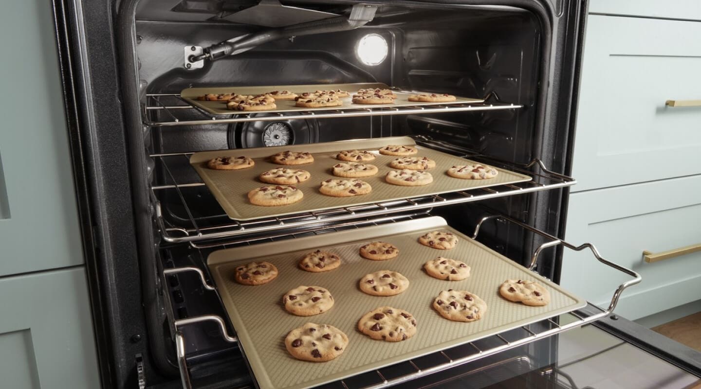 Three trays of cookies baking in an oven Three trays of cookies baking in an oven