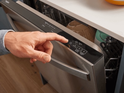 Person selecting a cycle on a top control dishwasher