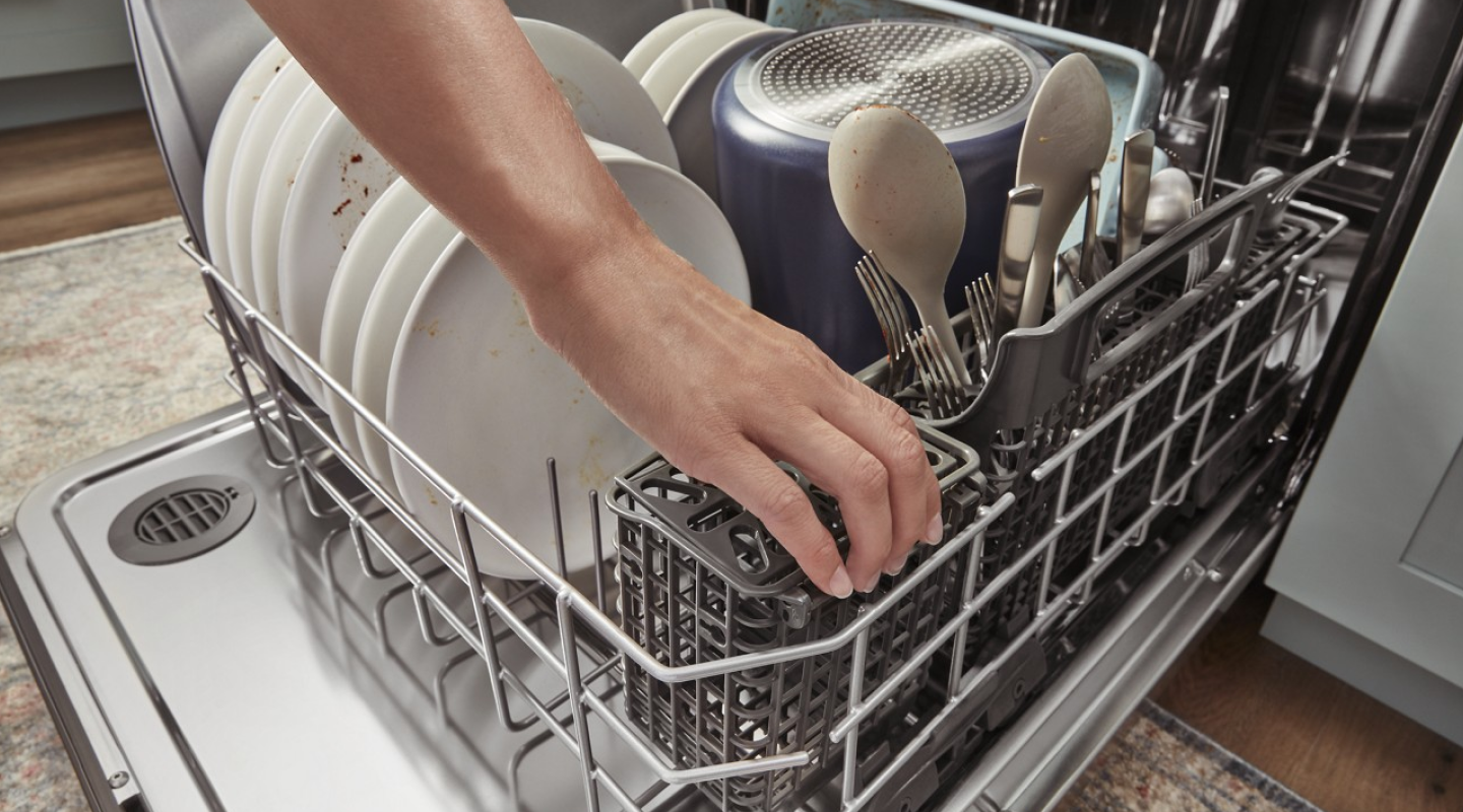 Hand reaching into a full dishwasher Hand reaching into a full dishwasher