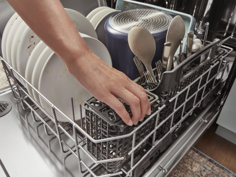 Hand reaching into a full dishwasher Hand reaching into a full dishwasher