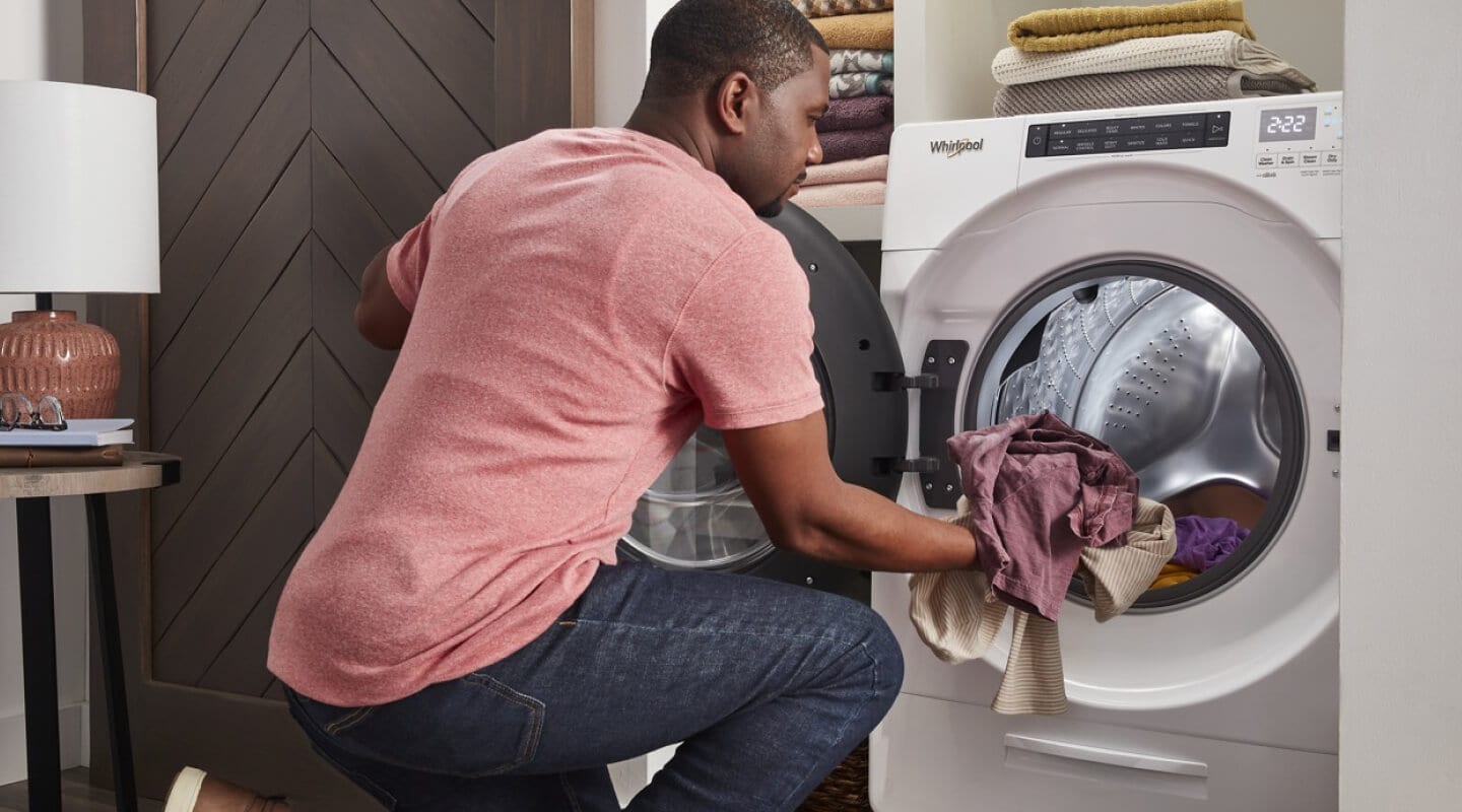 Person loading laundry into a white Whirlpool® Front Load Washer Person loading laundry into a white Whirlpool® Front Load Washer