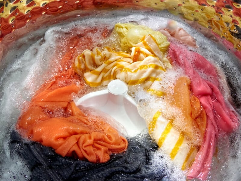Colorful laundry load soaking inside of a top load washer with an agitator Colorful laundry load soaking inside of a top load washer with an agitator