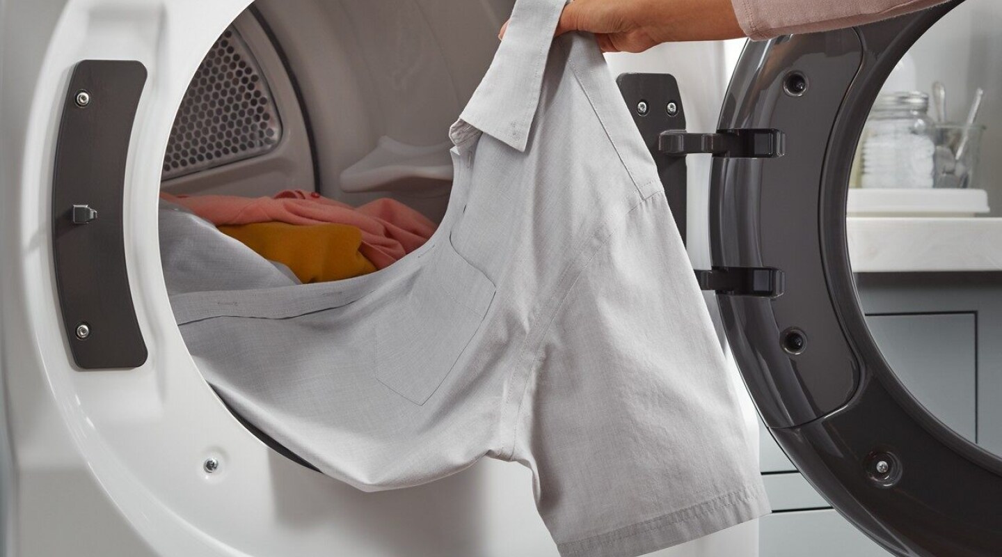 Person removing a shirt from a dryer Person removing a shirt from a dryer