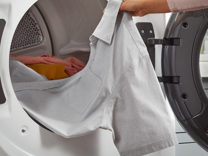 Person removing a shirt from a dryer Person removing a shirt from a dryer