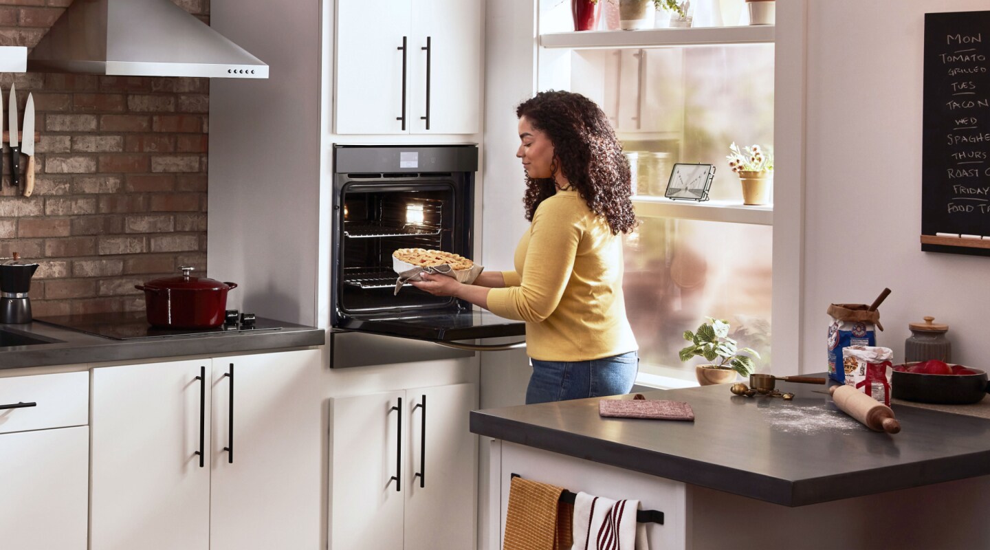 Woman using a Whirlpool®  single wall oven in a modern kitchen Woman using a Whirlpool®  single wall oven in a modern kitchen