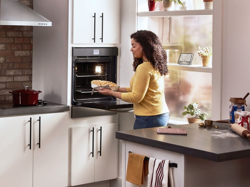 Woman using a Whirlpool®  single wall oven in a modern kitchen Woman using a Whirlpool®  single wall oven in a modern kitchen