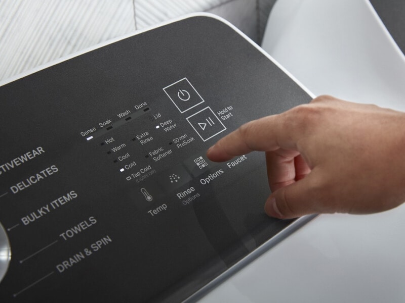 Person about to push a button on a washing machine Person about to push a button on a washing machine