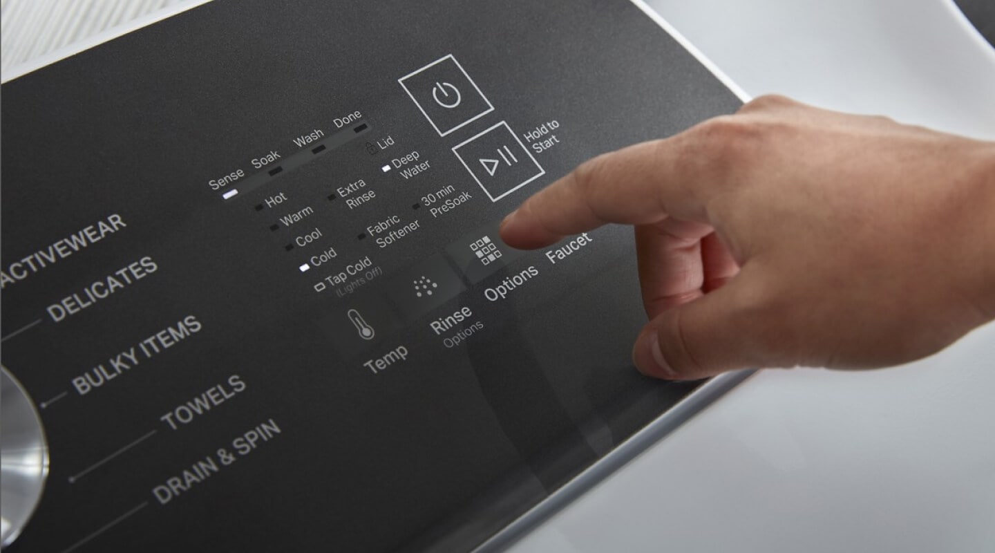 Person about to push a button on a washing machine Person about to push a button on a washing machine