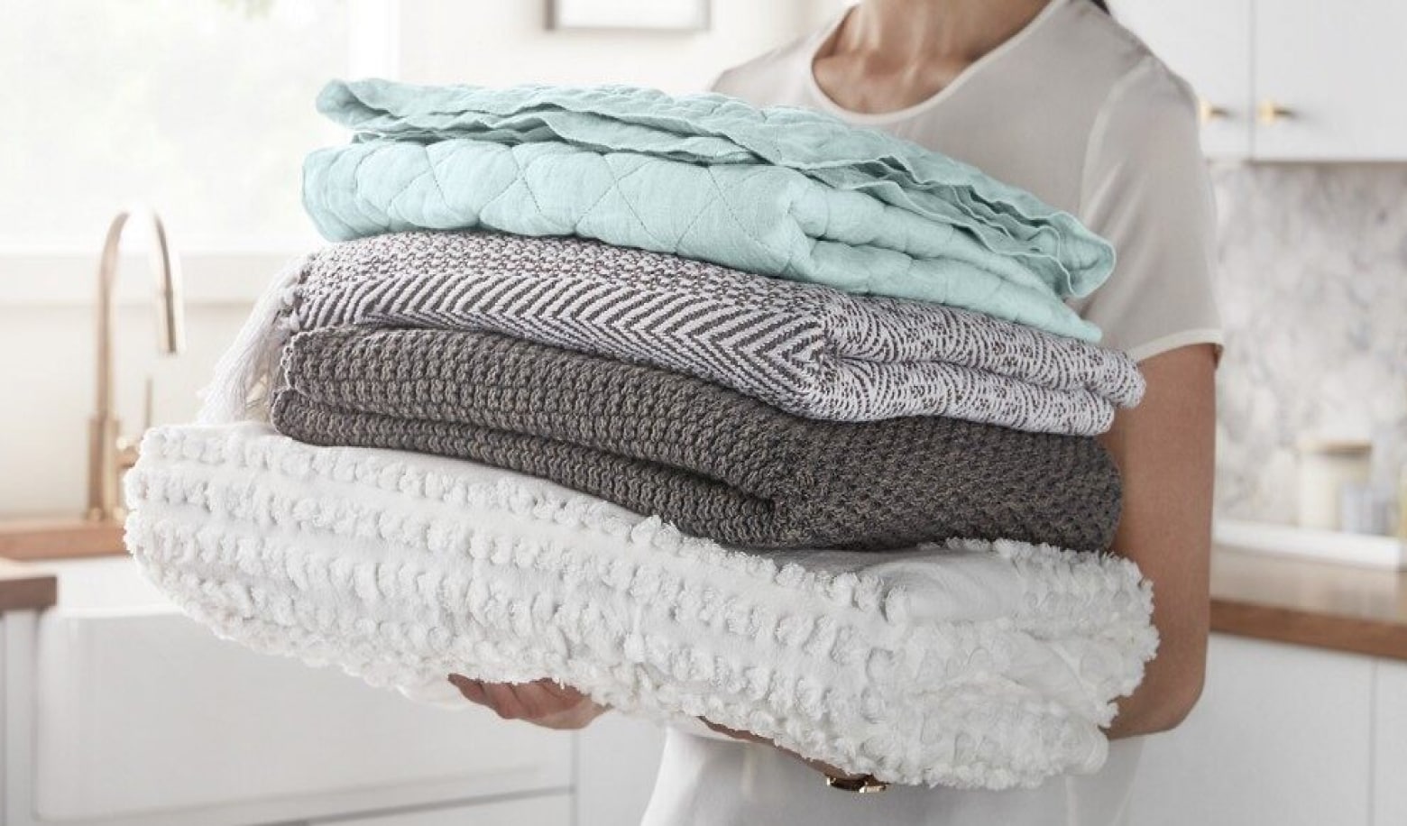 Woman carrying a stack of folded blankets