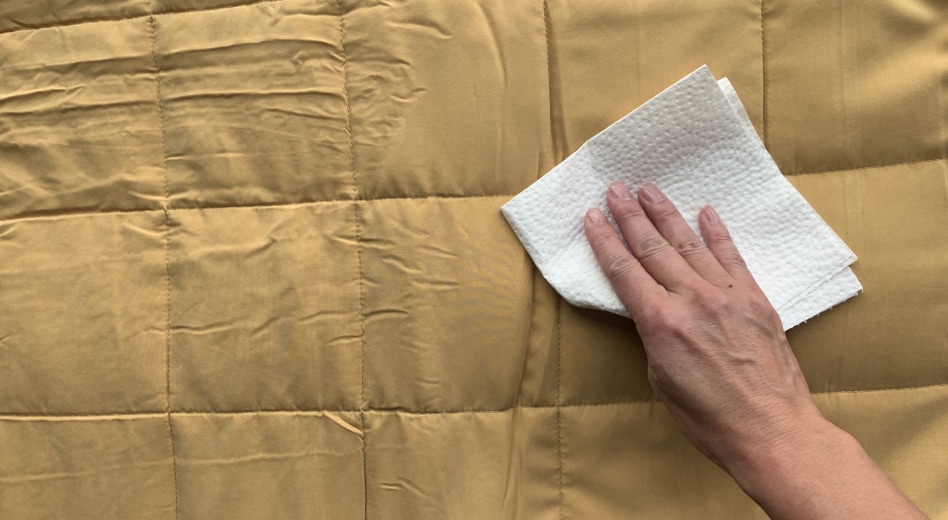 Person patting weighted blanket with a paper towel Person patting weighted blanket with a paper towel