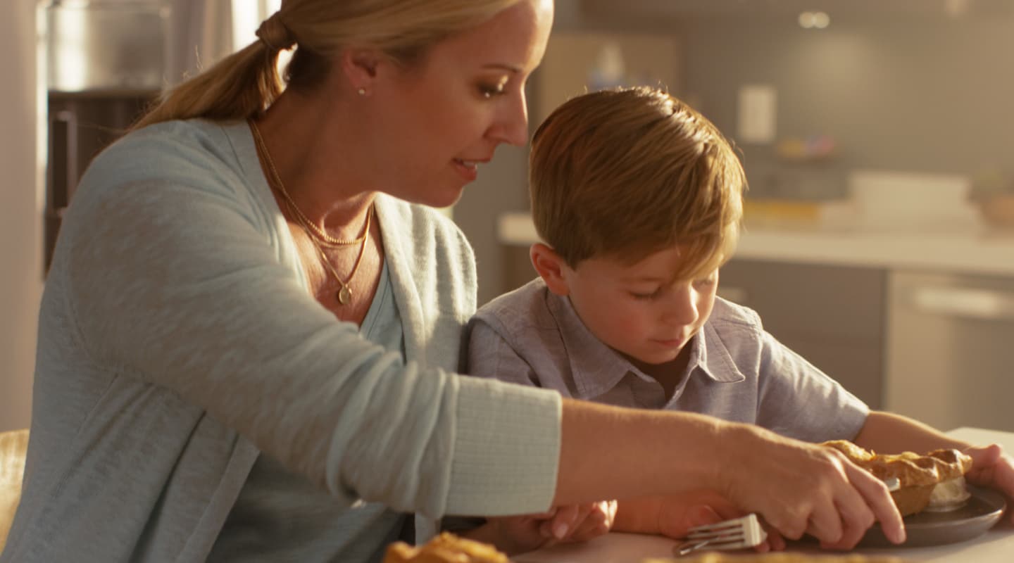 Adult and child serving pie at a kitchen island Adult and child serving pie at a kitchen island