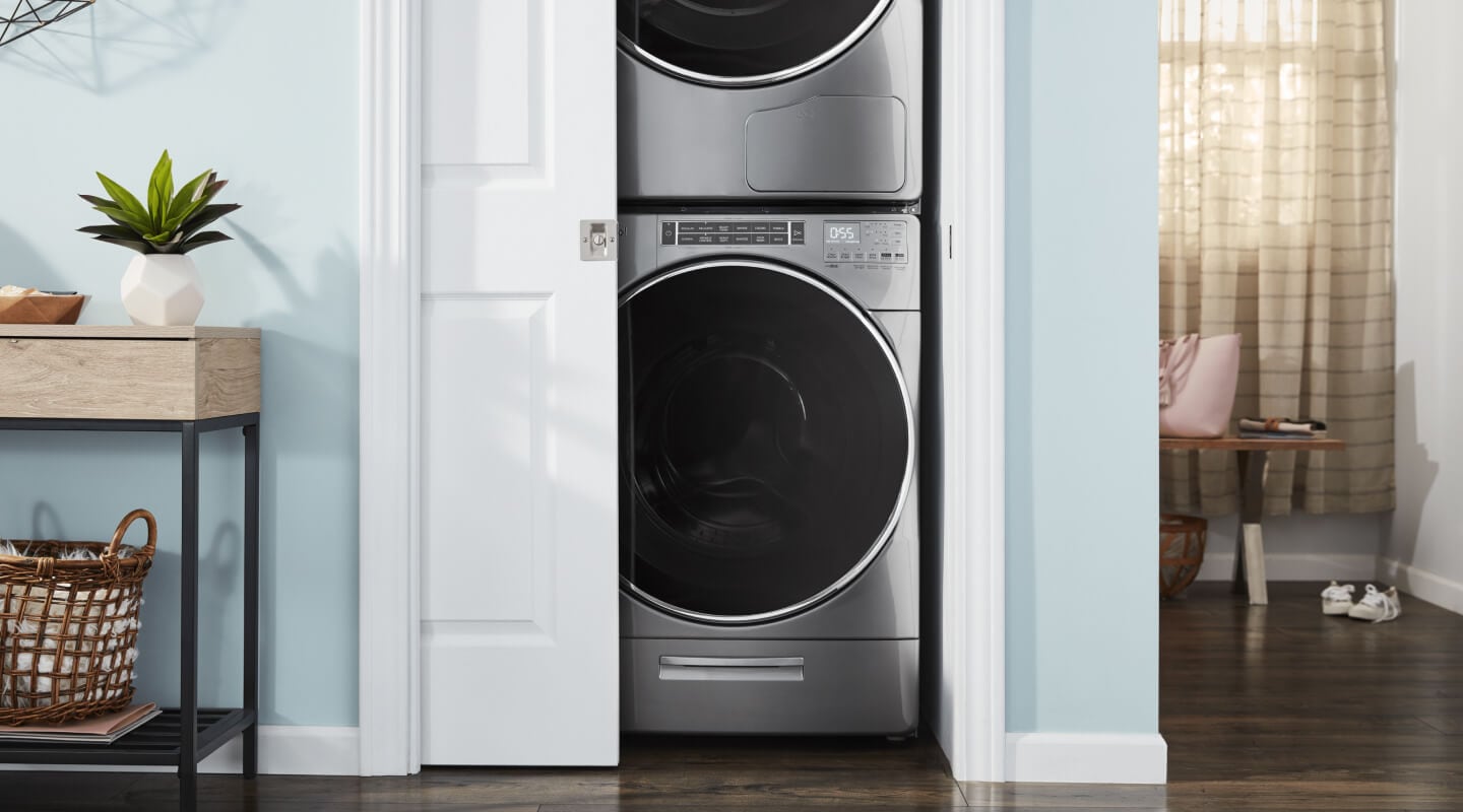 Stackable washer and dryer in a closet with door slightly ajar Stackable washer and dryer in a closet with door slightly ajar