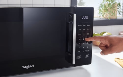 Person selecting a setting on a countertop microwave control panel