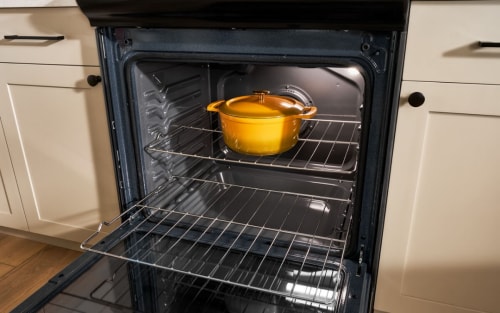 A yellow, slow cooking pot inside an oven