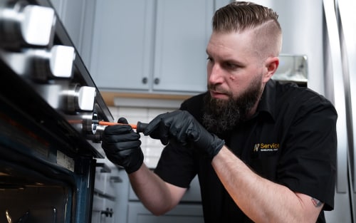 A technician working on a kitchen stove