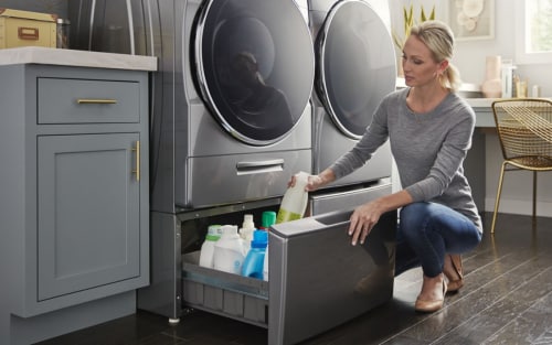 A person accessing laundry supplies in a pedestal drawer