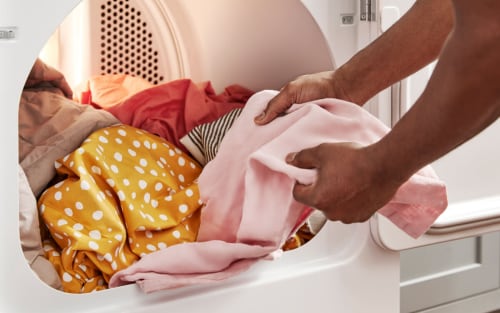 Person handling clothes in a dryer