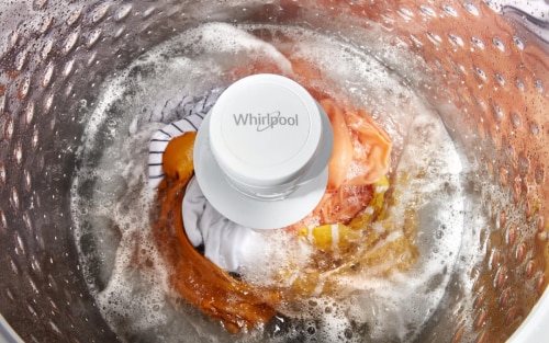 Orange fabric agitating in a Whirlpool® Top Load Washer full of water